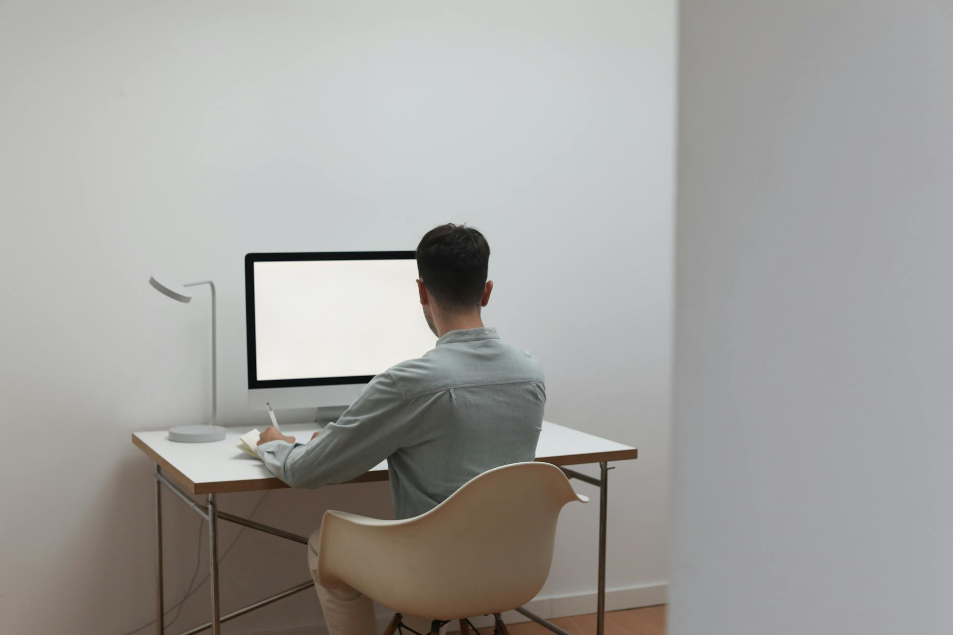 사무실 책상에서 수출바우처 포털 화면을 바라보며 고민하는 중년 남성의 뒷모습