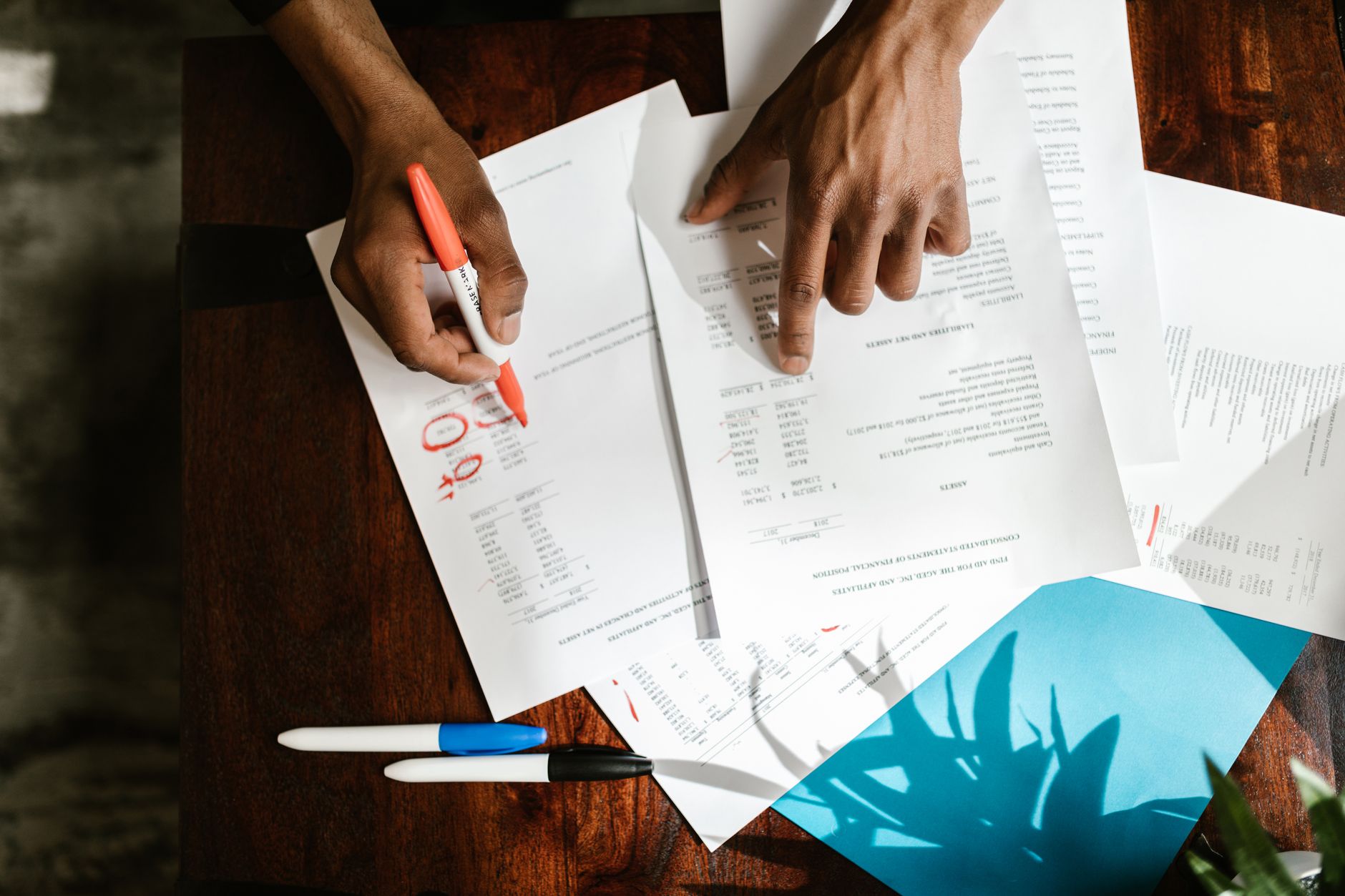 A developer sits at a desk with a thick stack of printed code, highlighting lines with a marker