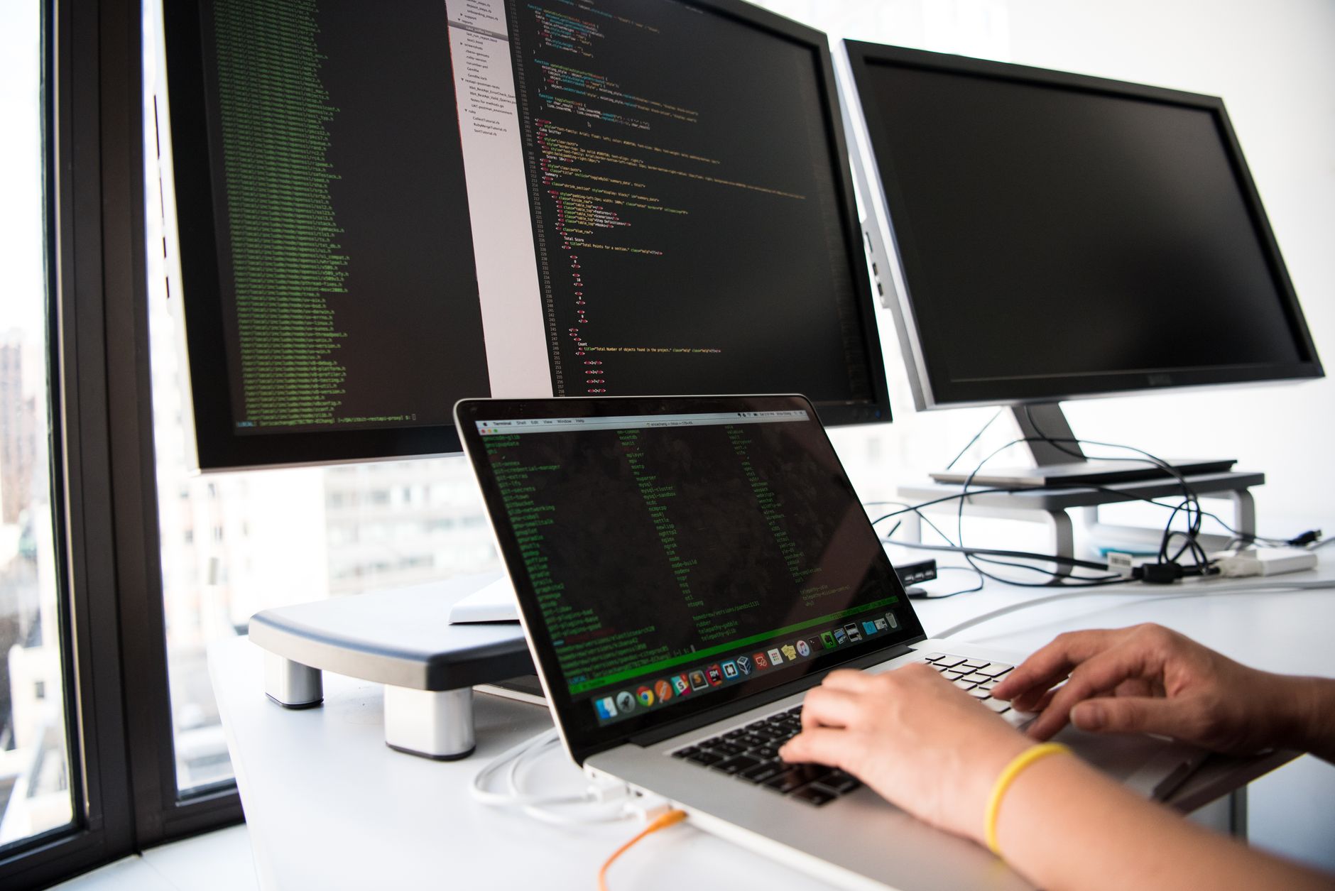 A developer sitting at a desk with multiple code editor tabs open, looking thoughtful rather than frustrated, coffee cup nearby