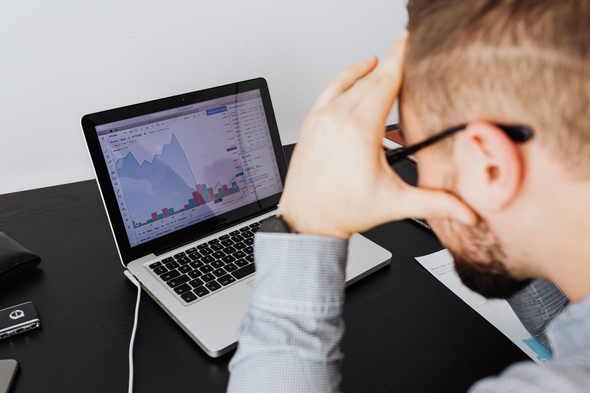 Image prompt: Back view of a tired global buyer bulk-deleting a long list of emails with identical subject lines on a laptop screen