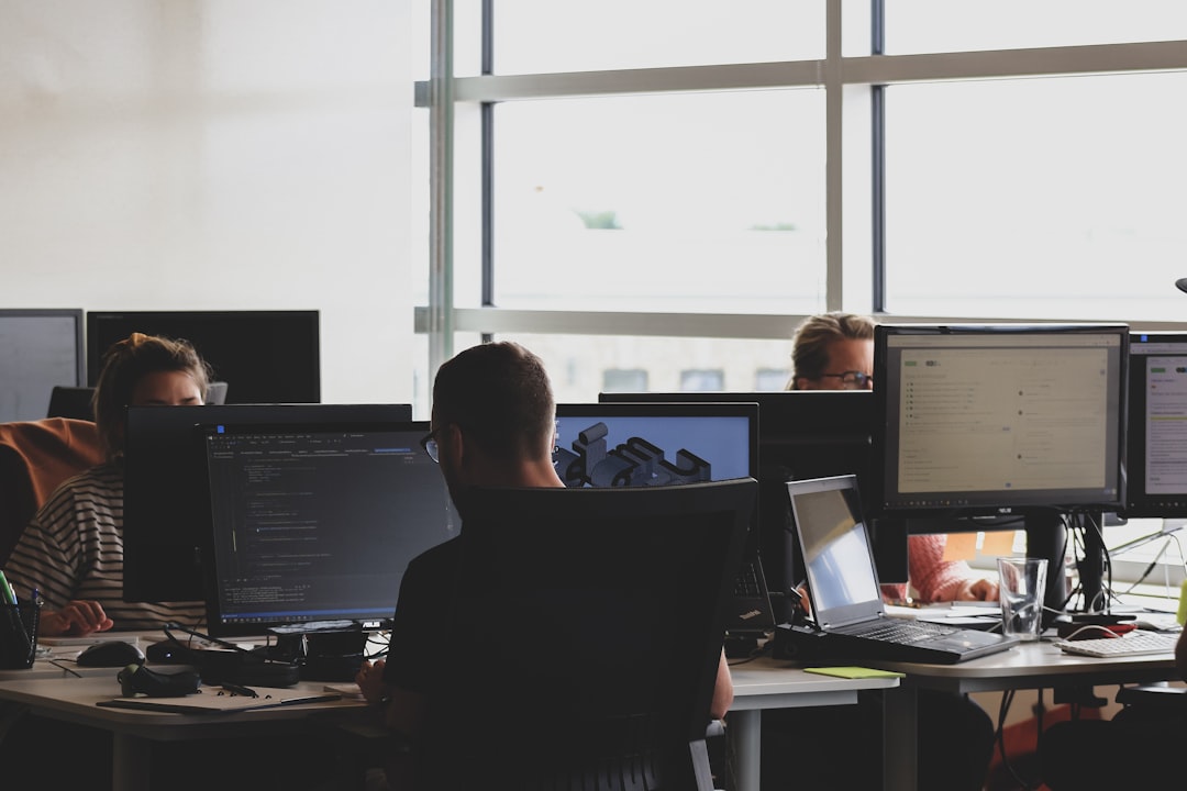Two developers in a small office reviewing code together on a monitor — one points at the screen with a tense expression